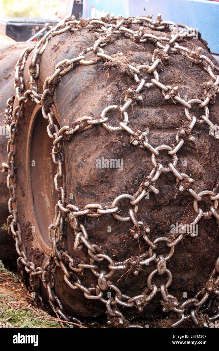Die Details der Räder und Reifen des landwirtschaftlichen Fahrzeugs. Ausgestattet mit Reifenketten zum Fahren im Schlamm. Stockfoto