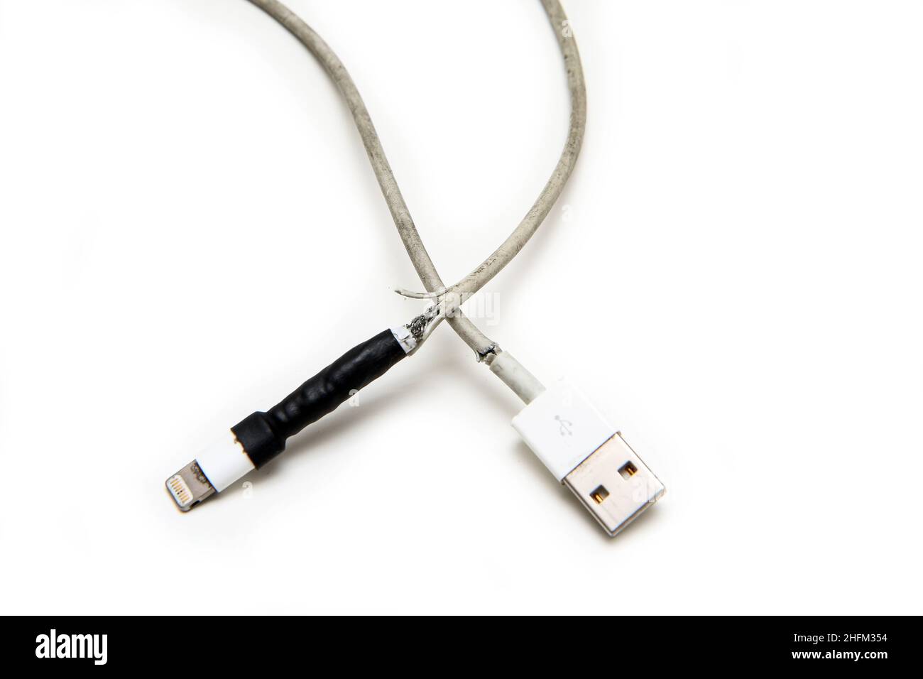 Das Detail eines Smartphones Ladegerät mit gebrochenem und ausgefranstem Kabel. Schon einmal mit Band fixiert, aber wieder gebrochen. Typisches Problem der Benutzer. Stockfoto