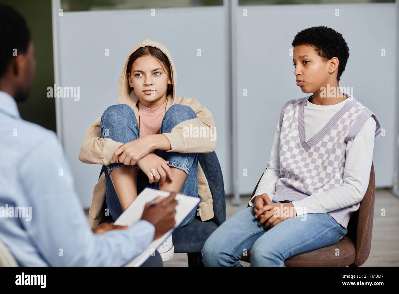 Portrait von zwei Mädchen im Teenageralter, die in einer Therapiesitzung mit einem Psychologen sprechen Stockfoto