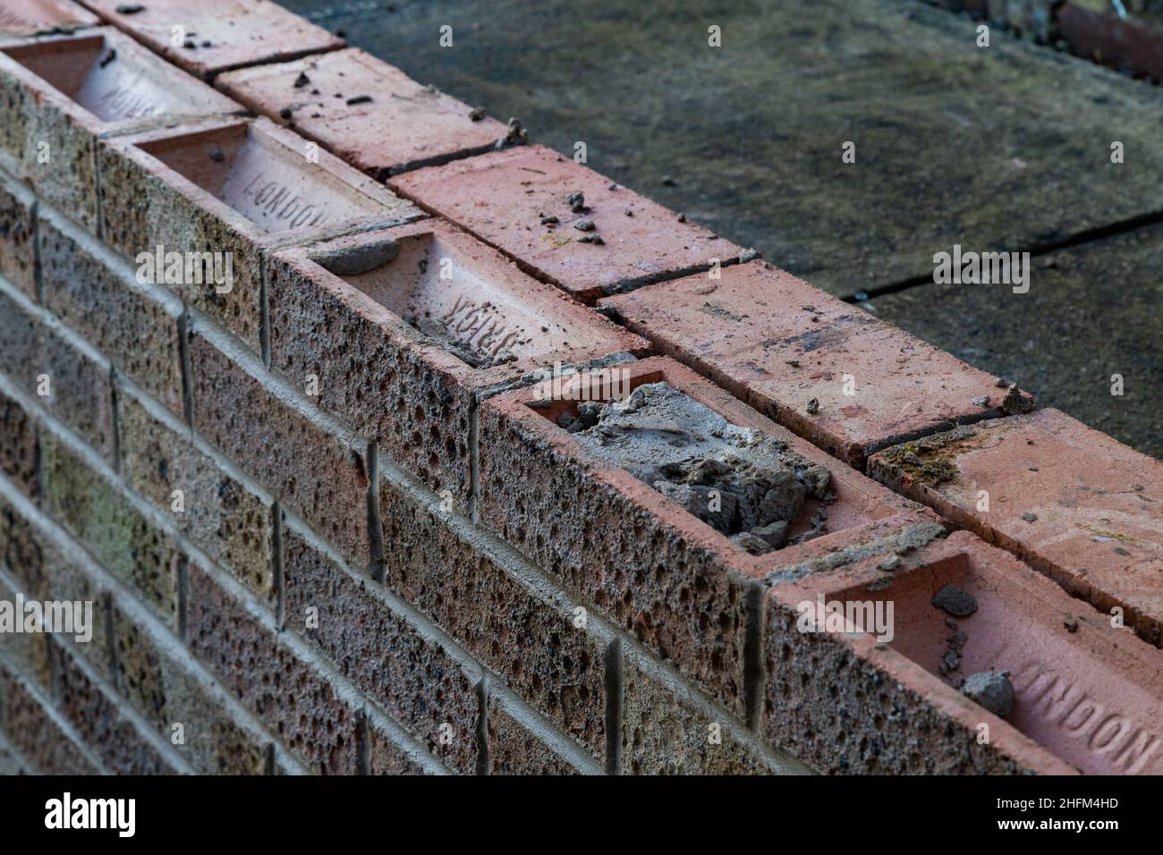 Eine solide, doppelziegelige Gartenmauer wird gebaut. Stockfoto