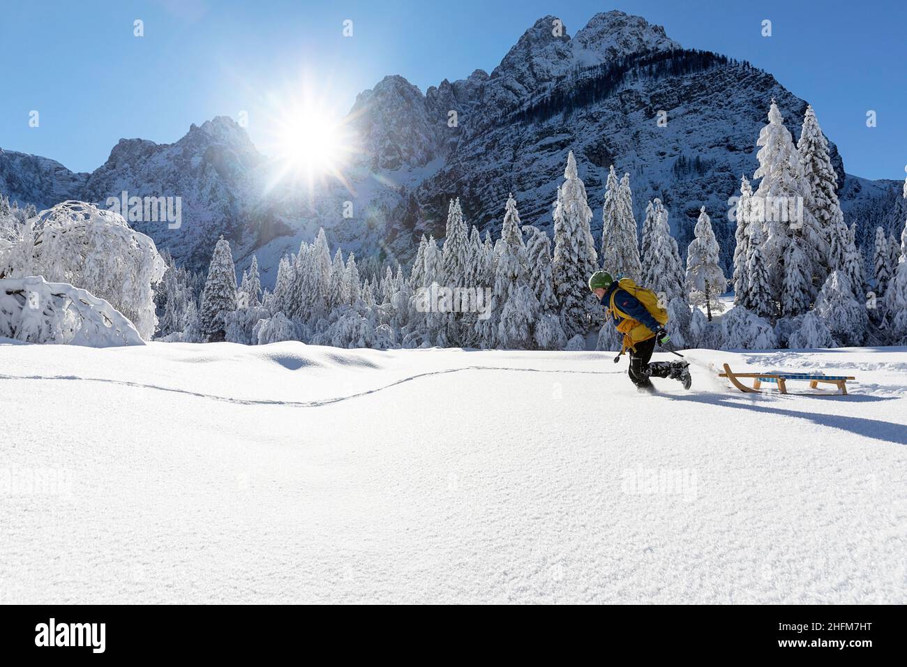 Lächelnder Junge, der im tiefen Schnee in der wunderschönen Winterlandschaft im Krnica-Tal, Slowenien, läuft und Schlitten zieht Stockfoto