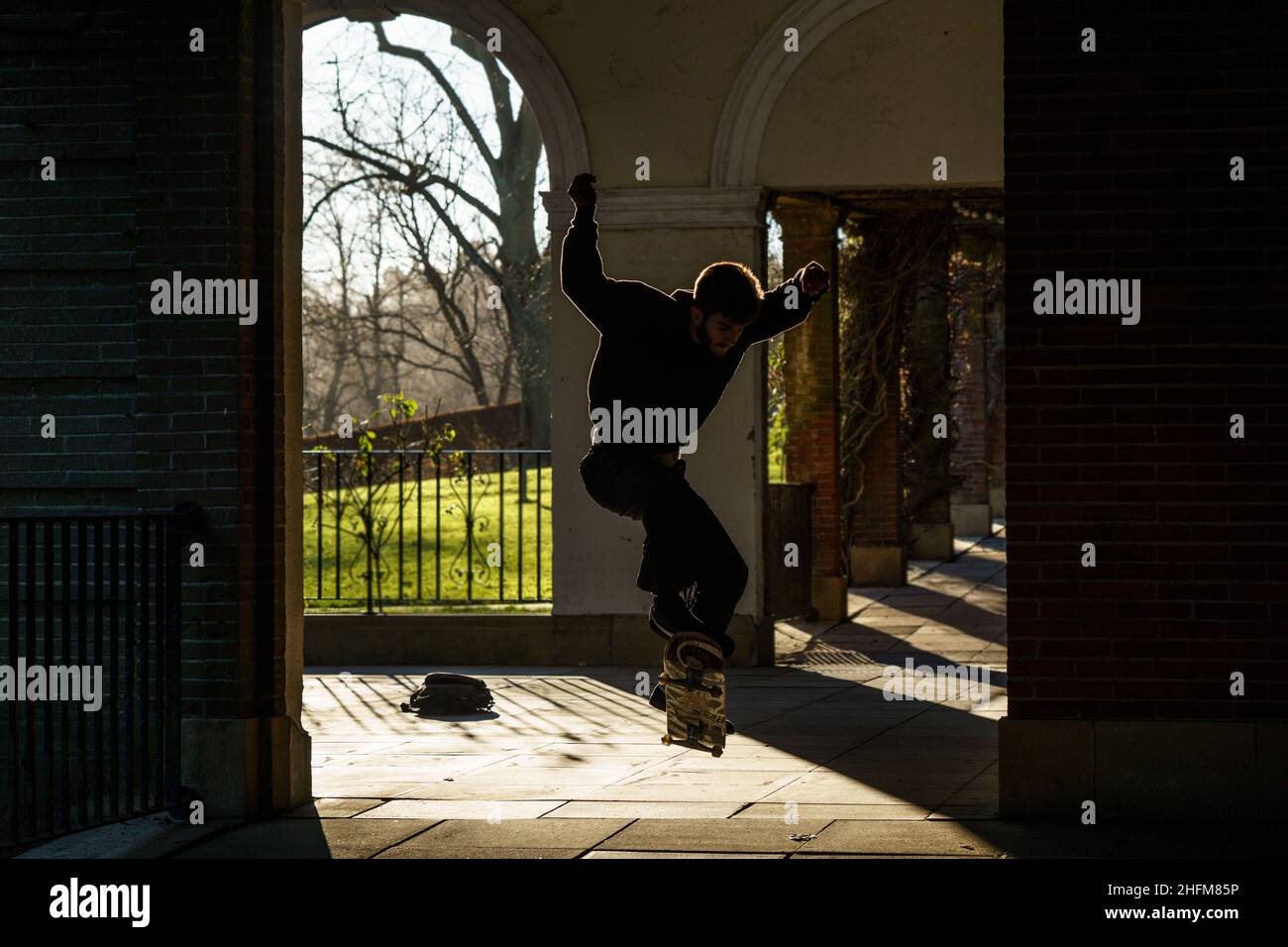 Ein Skateboarder in Valley Gardens, Harrogate, hebt seine Arme in der Luft, während er einen riesigen Luftsprung in North Yorkshire, England, durchführt. Stockfoto