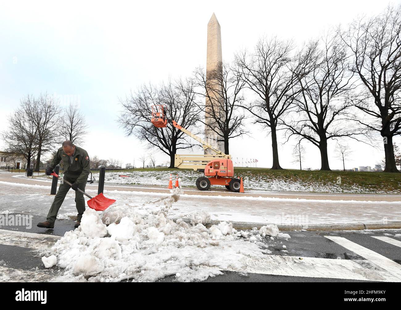 Ein Mitarbeiter des National Park Service schaufelt nach einer stürmischen Nacht in Washington, USA, am 17. Januar 2022 Schnee in der Nähe des Washington Monument. REUTERS/Mike Theiler Stockfoto