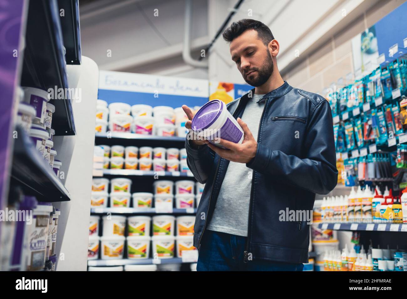 Ein Mann in einem Baumarkt wählt Farbe für Reparaturen im Haus Stockfoto