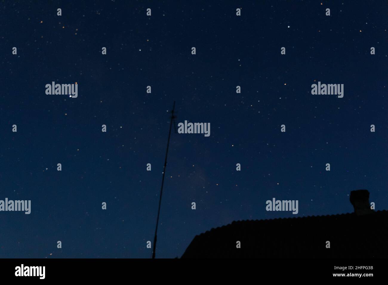 Unschärfen Sie den schönen Nachthimmel. Haus, Dach, Kamin und Antenne. S Stockfoto