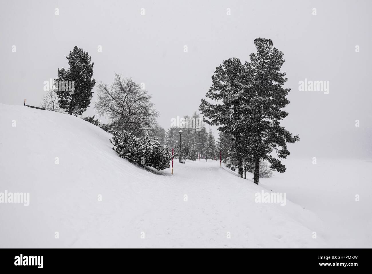 Die Promenade entlang des zugefrorenen St. Moritzer Sees an einem verschneiten Wintertag im Kanton Graubünden in den alpen in der Schweiz Stockfoto