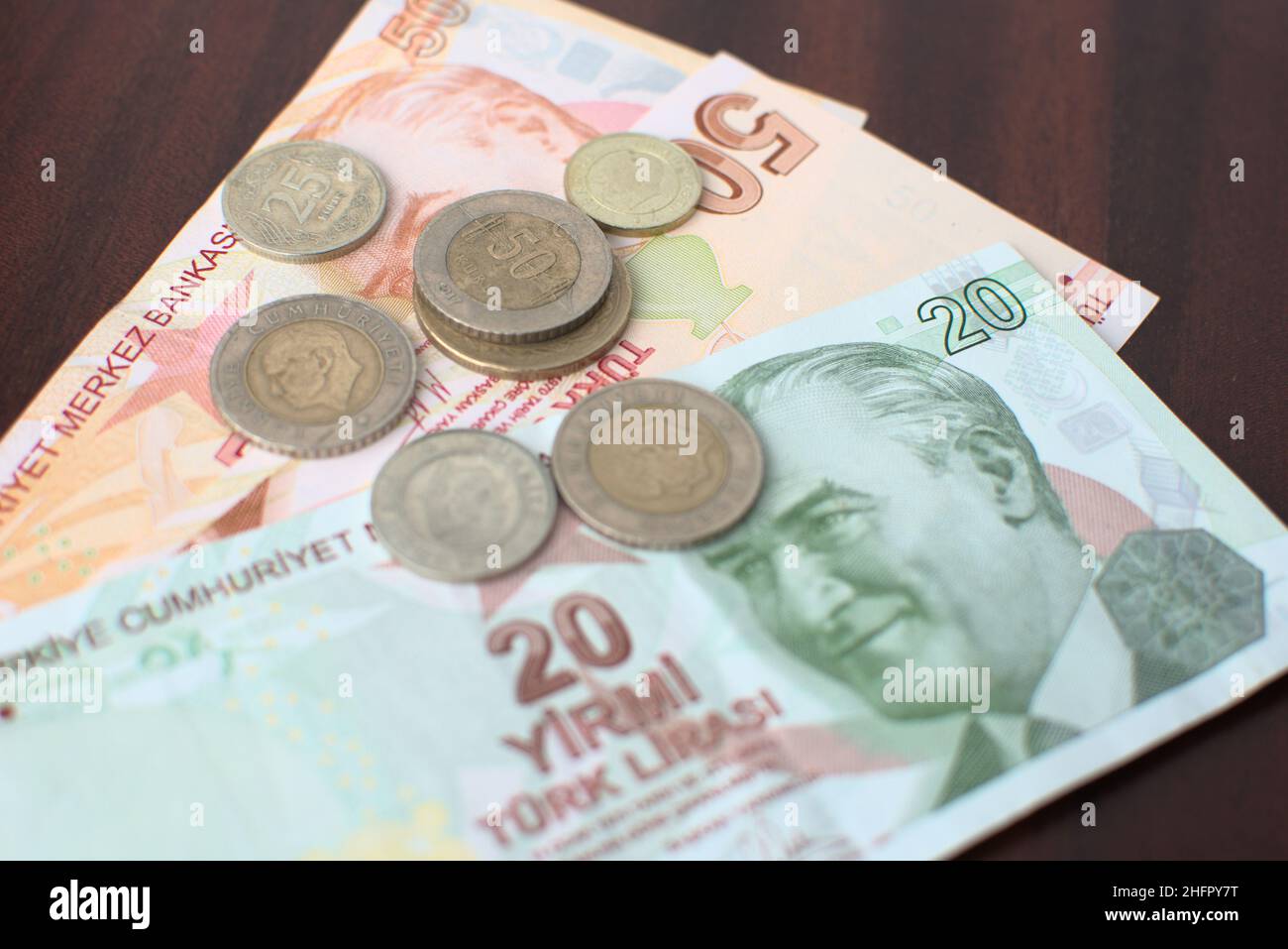 Einige türkische Banknoten und Münzen auf braunem Hintergrund. Einige türkische Liras für die Zahlung der Rechnungen auf einem braunen Tisch. Stockfoto
