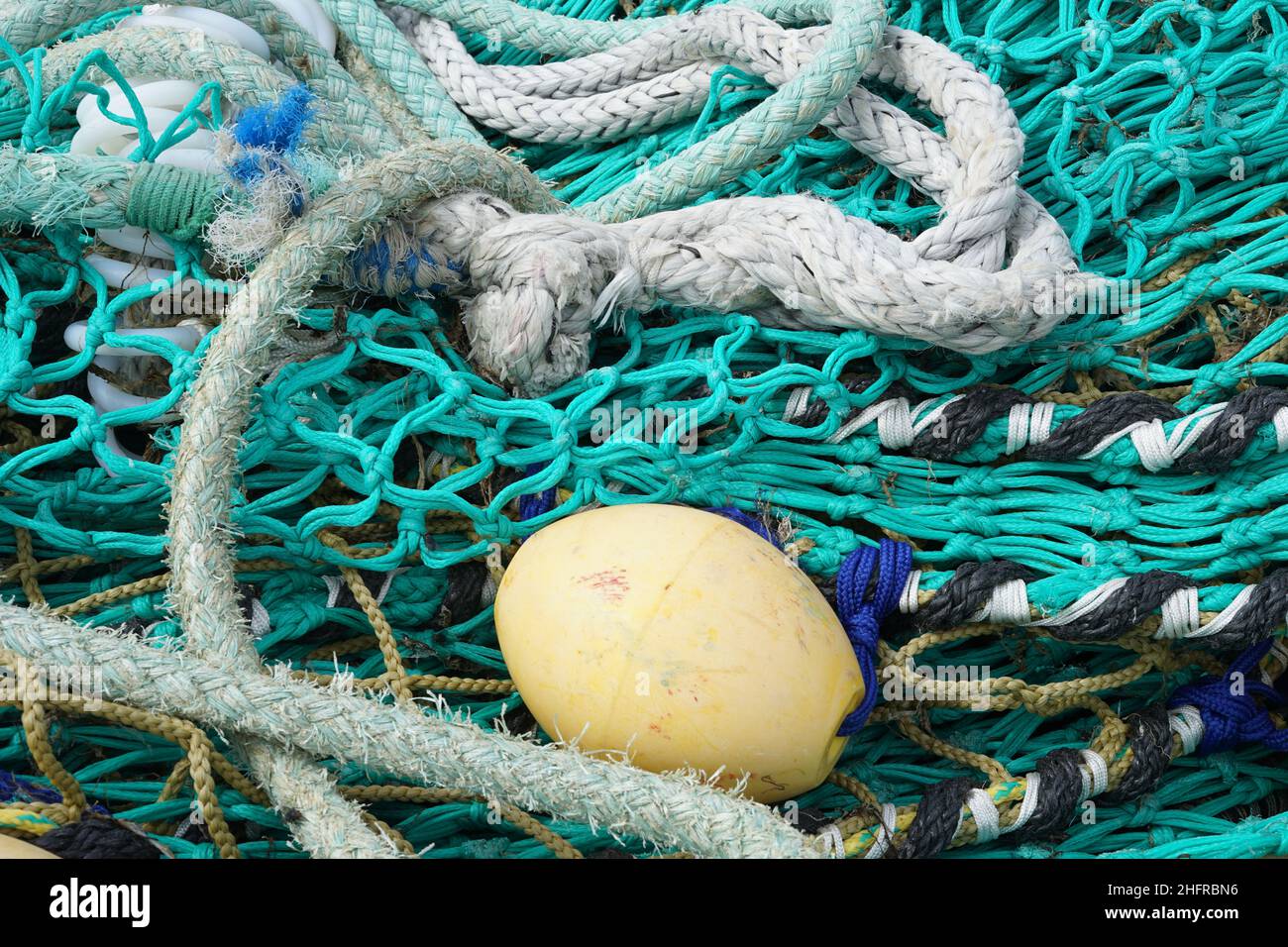 Türkisfarbene Fischernetze und weiße Seile, die in Schlaufen am Pier liegen Stockfoto