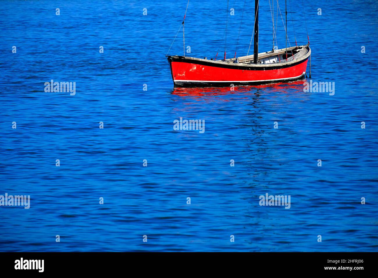 Rotes Segelboot schwimmt im Wasser an See- oder Ozeanbooten Stockfoto