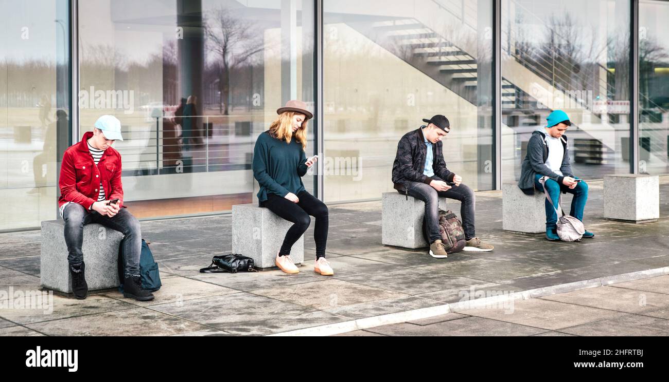 Teenager-Gruppe mit Smartphone sitzt auf College-Hinterhof Pause - Junge Menschen süchtig nach mobilen Smartphones - Technologiekonzept Stockfoto