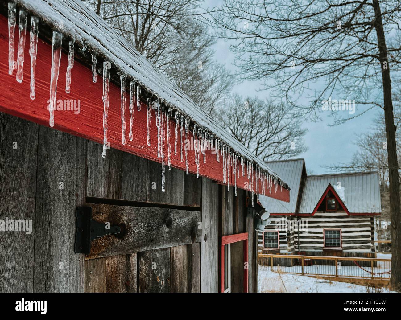 Eiszapfen säumen an einem kalten Wintertag das Dach eines Hauses. Stockfoto