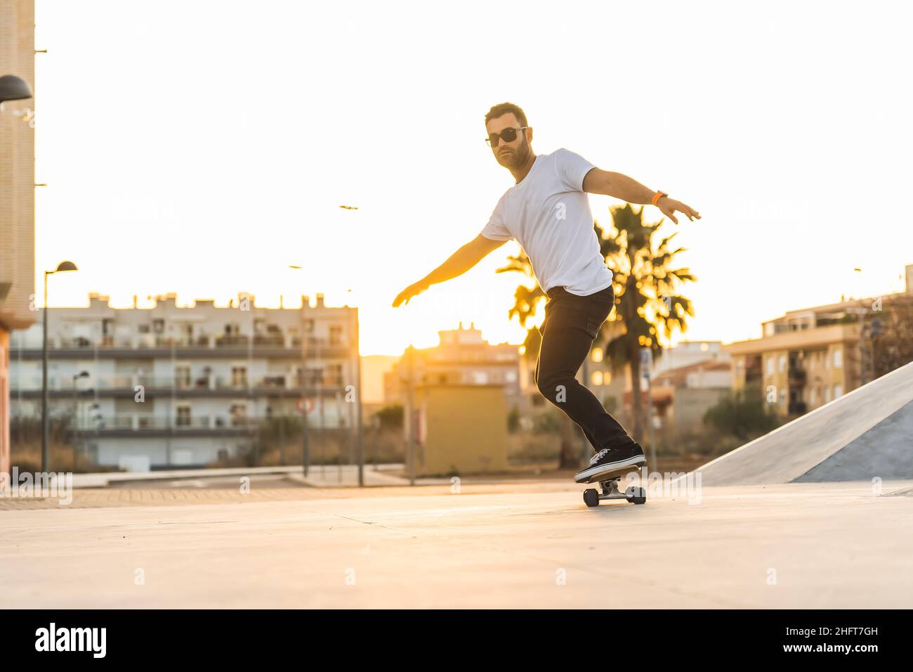 Erwachsener Mann genießt Skate Surf im Park bei Sonnenuntergang Stockfoto