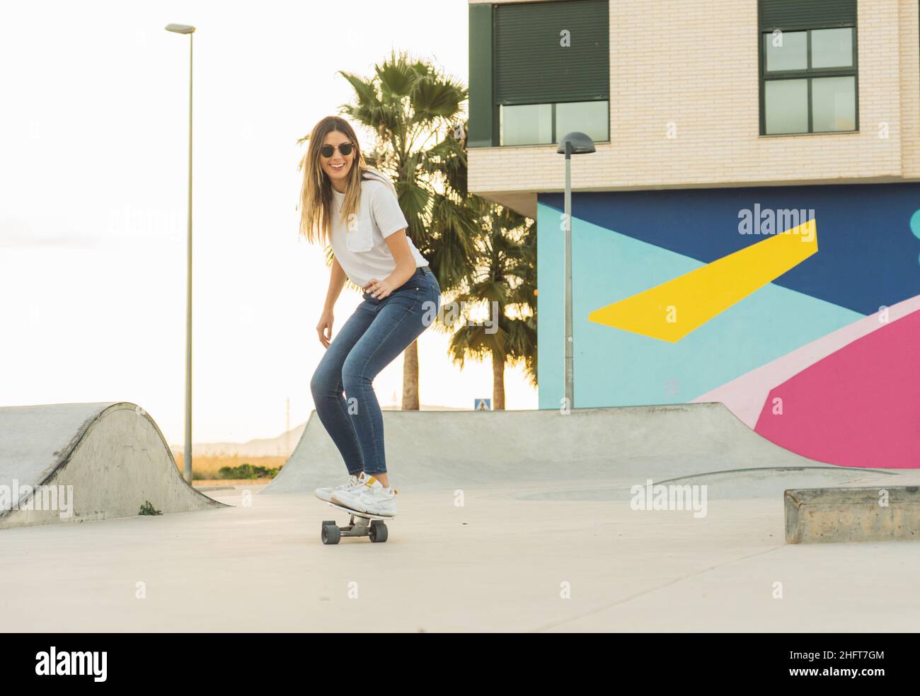Junge Frau glücklich Skaten mit Surf Skate im Park bei Sonnenuntergang Stockfoto