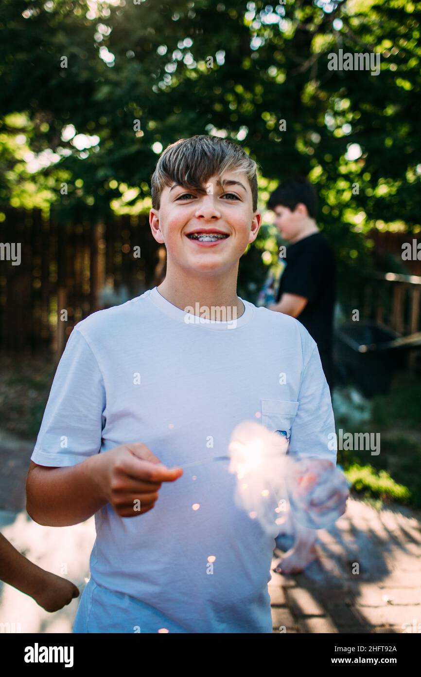 Glücklich teen junge spielen mit funkler draußen Stockfoto