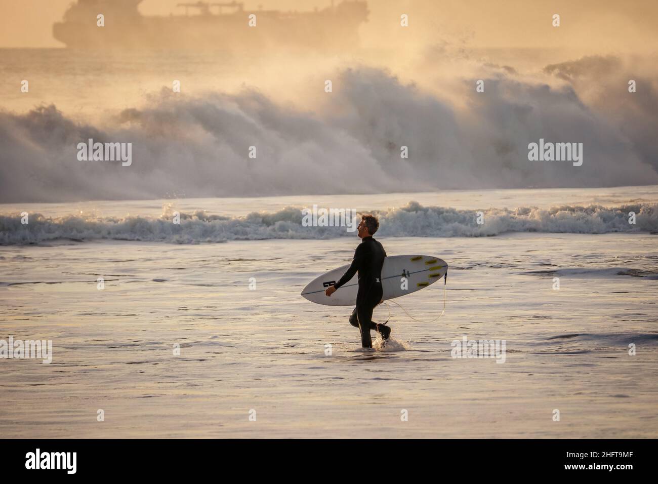 Surfer mit Surfbrett zum Surfen am Strand Stockfoto