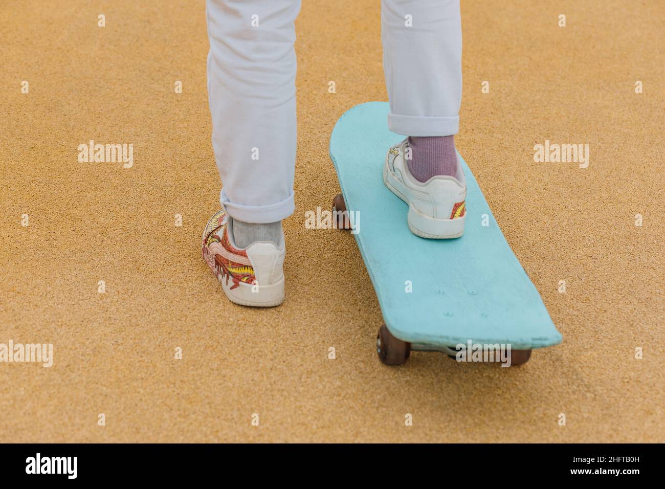 Rückansicht einer nicht erkennbaren Person mit Beinen auf dem Skateboard. Stockfoto