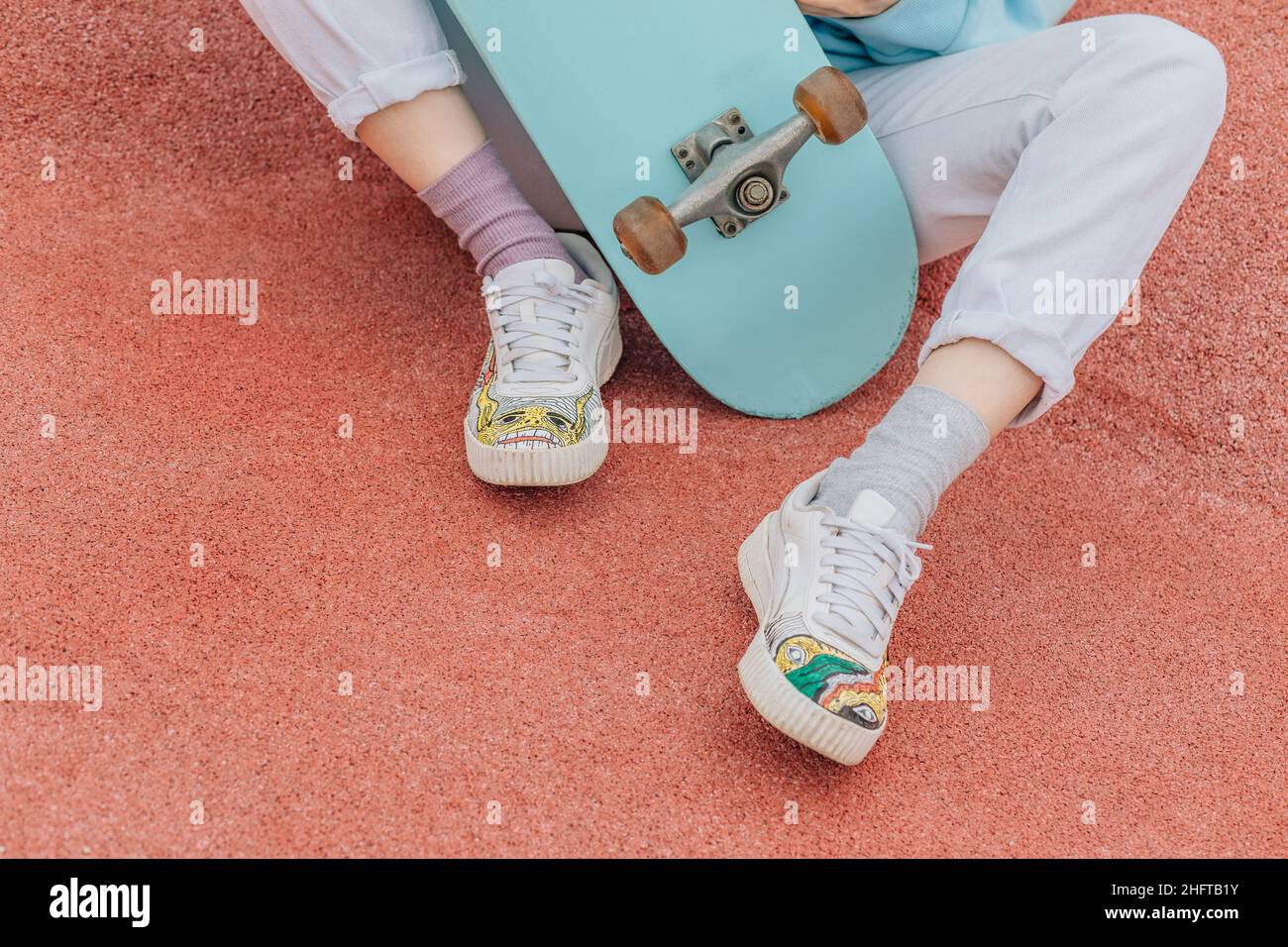 Nicht erkennbare Person auf Skateboard, Beine in Sneakers mit Schnürsenkeln. Stockfoto