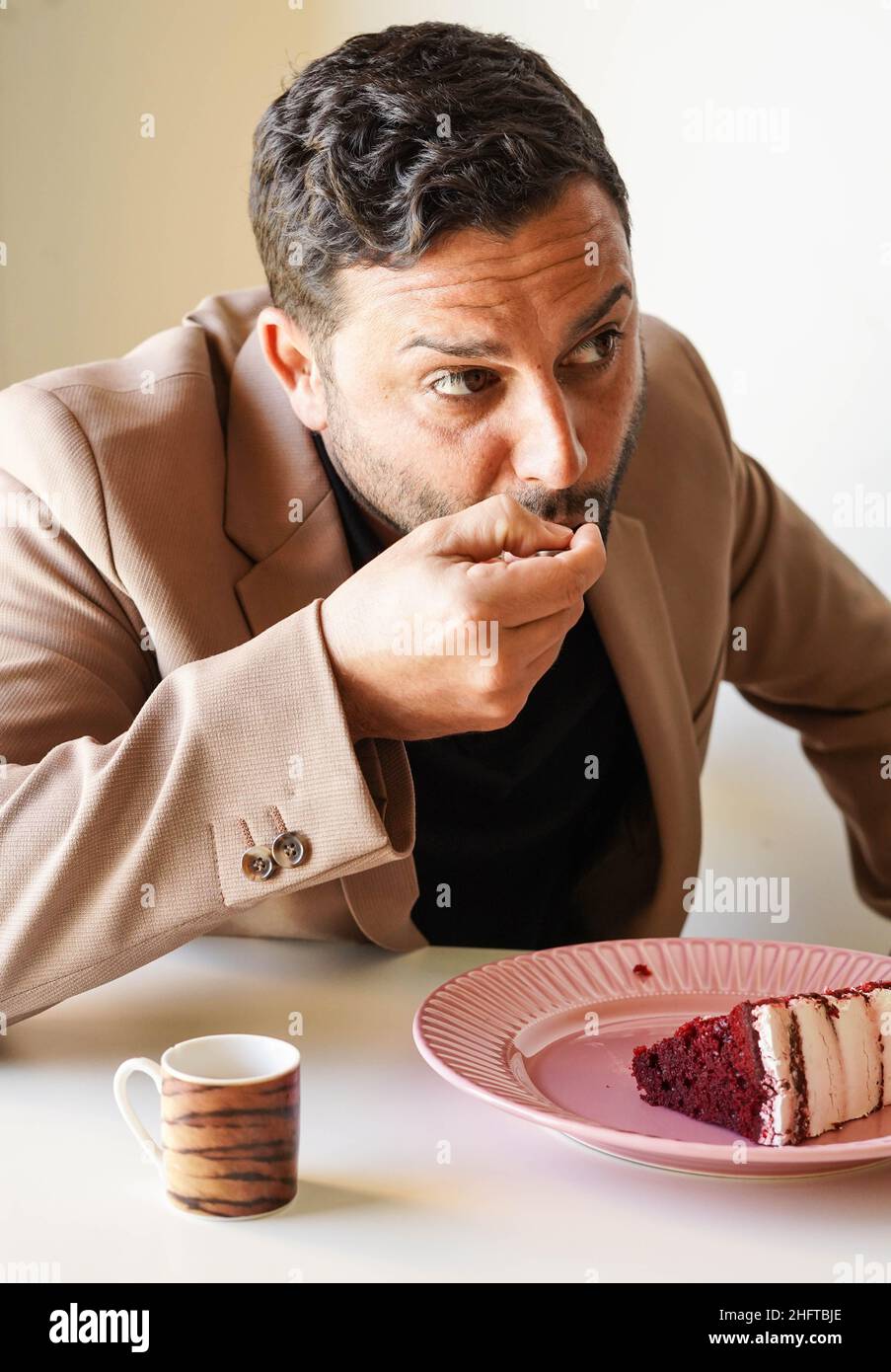 Mann genießt roten Samtkuchen und Kaffee in der Arbeitspause Stockfoto