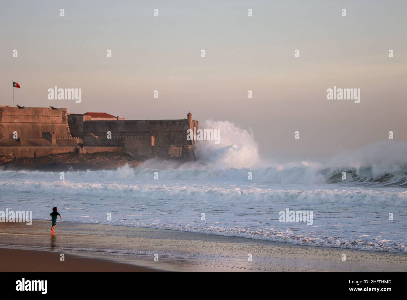 Große Wellen stürzen in eine Festung in der Nähe eines Strandes. Stockfoto