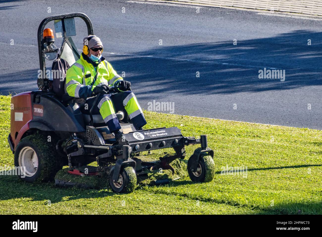 Arbeiter mähen an sonnigen Tagen im Freien Rasen mit einem Rasentrimmer Stockfoto