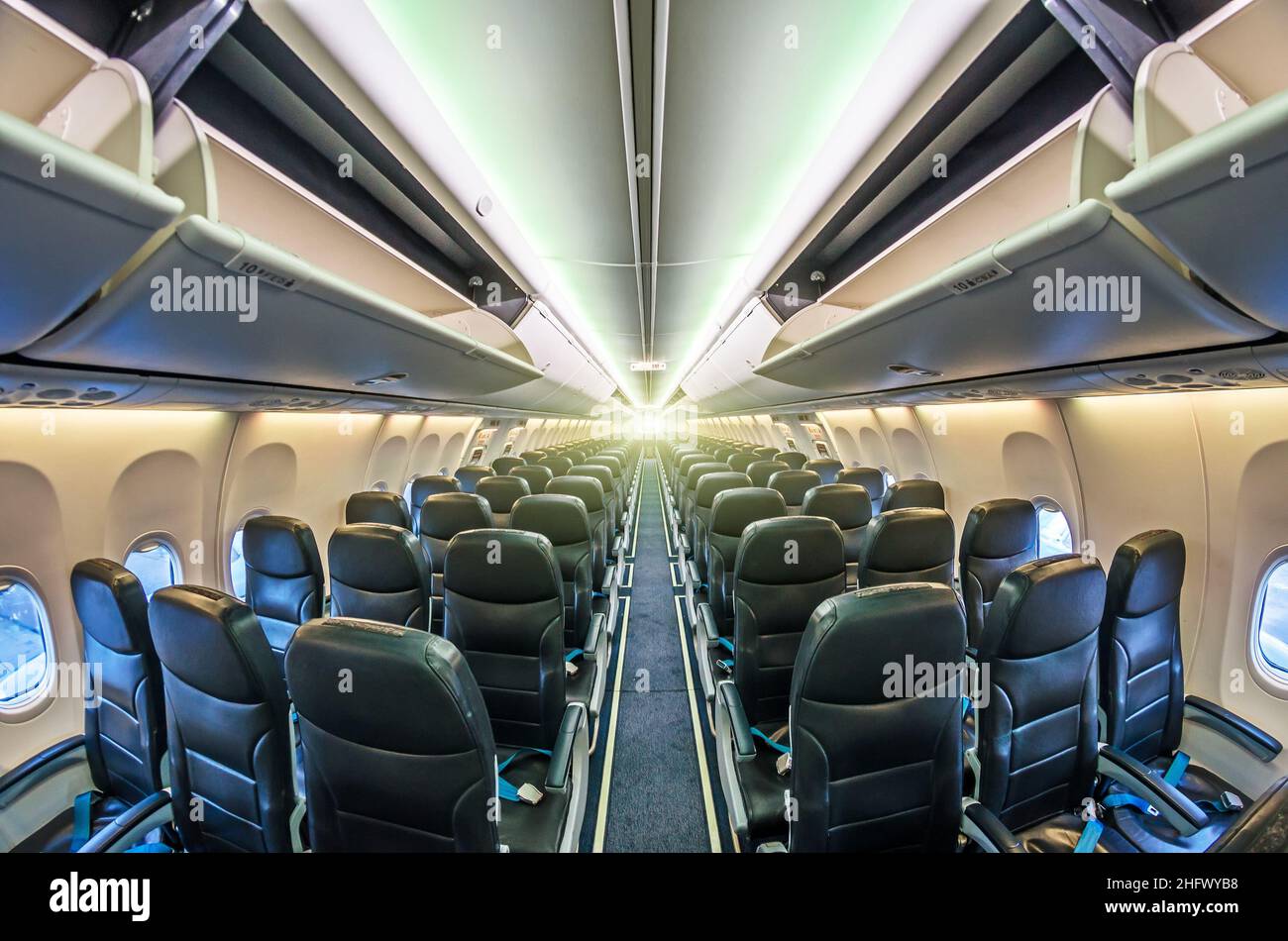 Durchgang in der Mitte des Flugzeugs zwischen den Passagiersitzen, mit offenen Regalen für Handgepäck Stockfoto