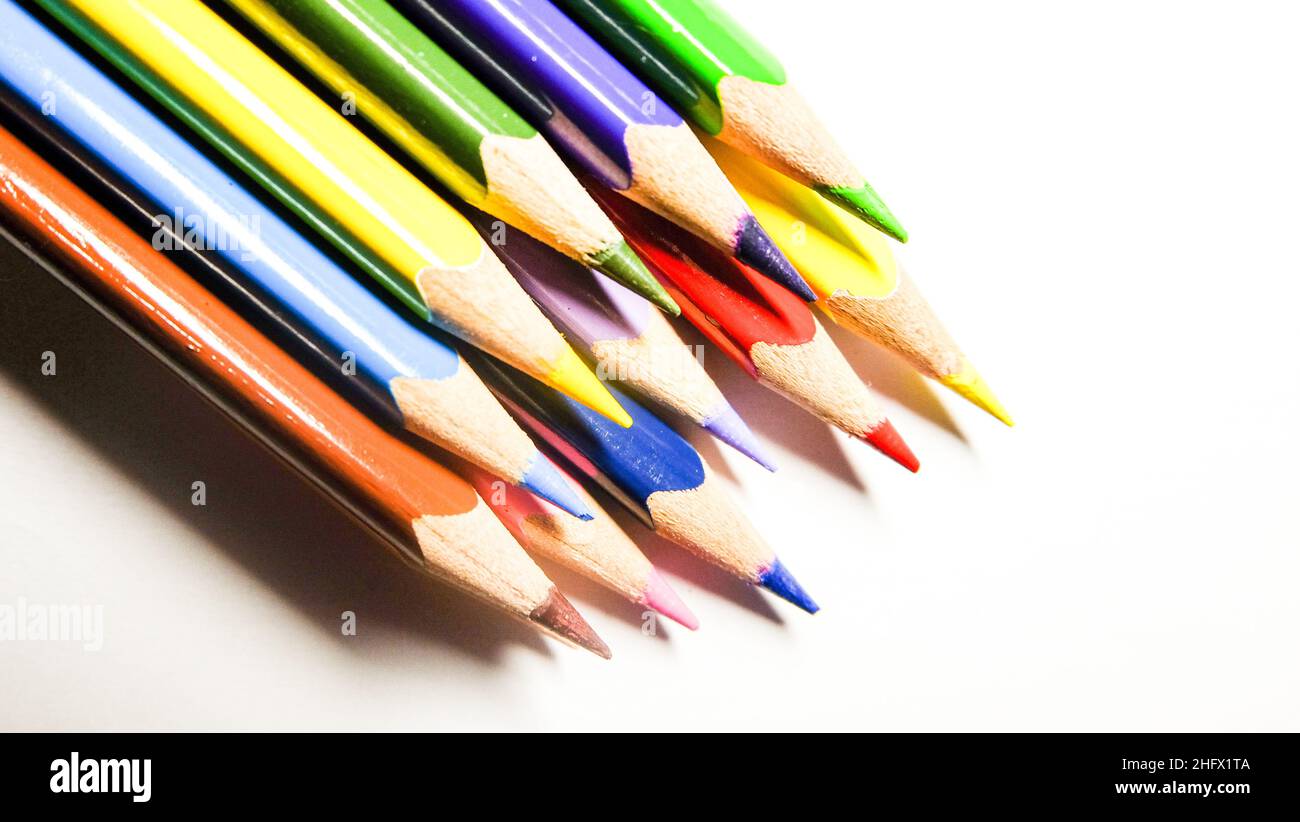 Farbstifte angeordnet, um einen Regenbogen auf weißem Hintergrund zu bilden. Isolierte Nahaufnahme für Schulprojekte. Stockfoto