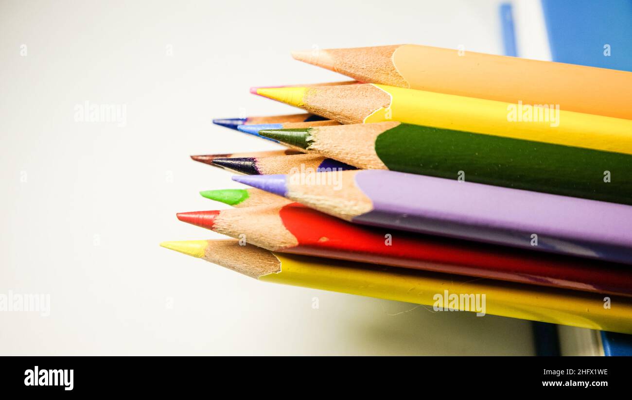 Farbstifte auf Notizbuch auf weißem Hintergrund angeordnet. Isolierte Nahaufnahme für Schulprojekte. Stockfoto