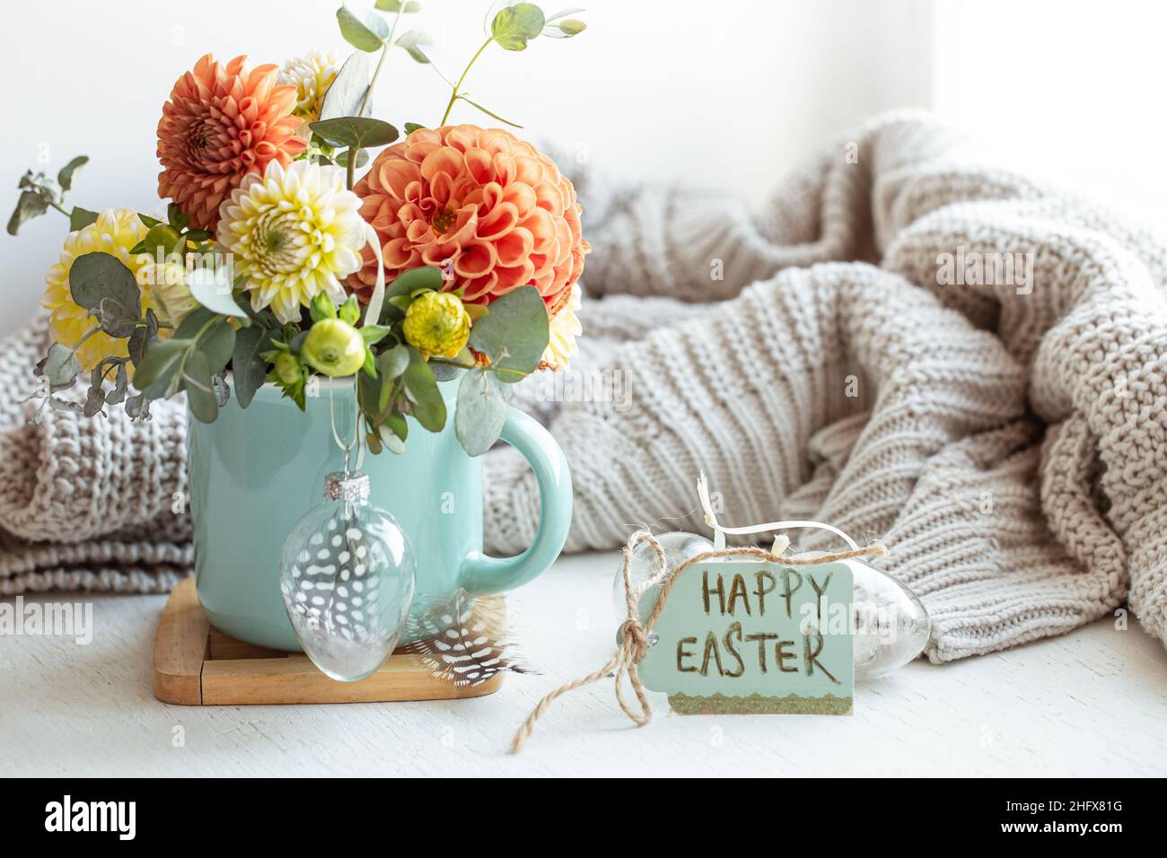 Osterkomposition mit einem Blumenstrauß und einem gestrickten Element. Stockfoto