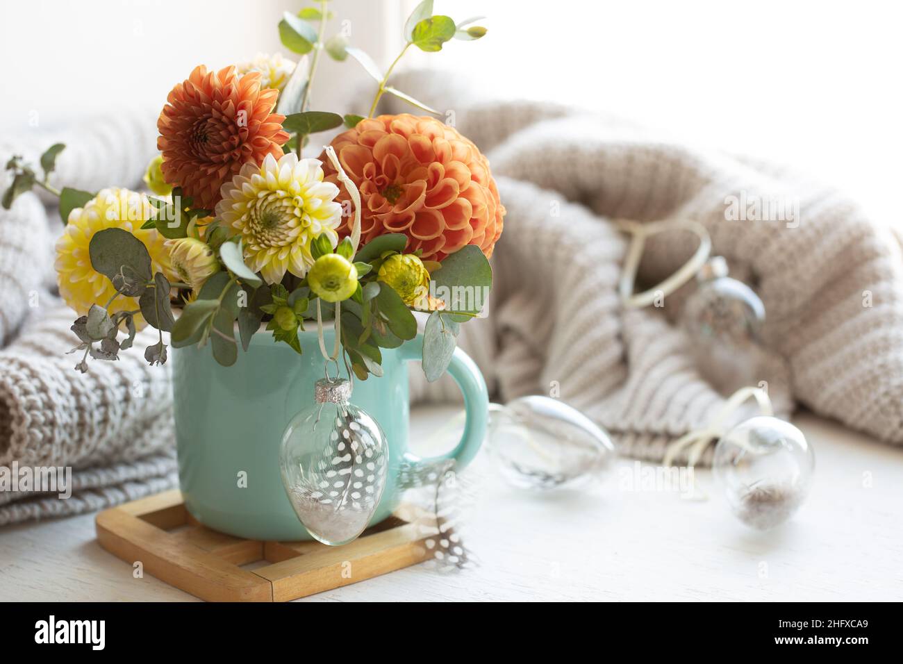 Osterkomposition mit einem Blumenstrauß und einem gestrickten Element. Stockfoto