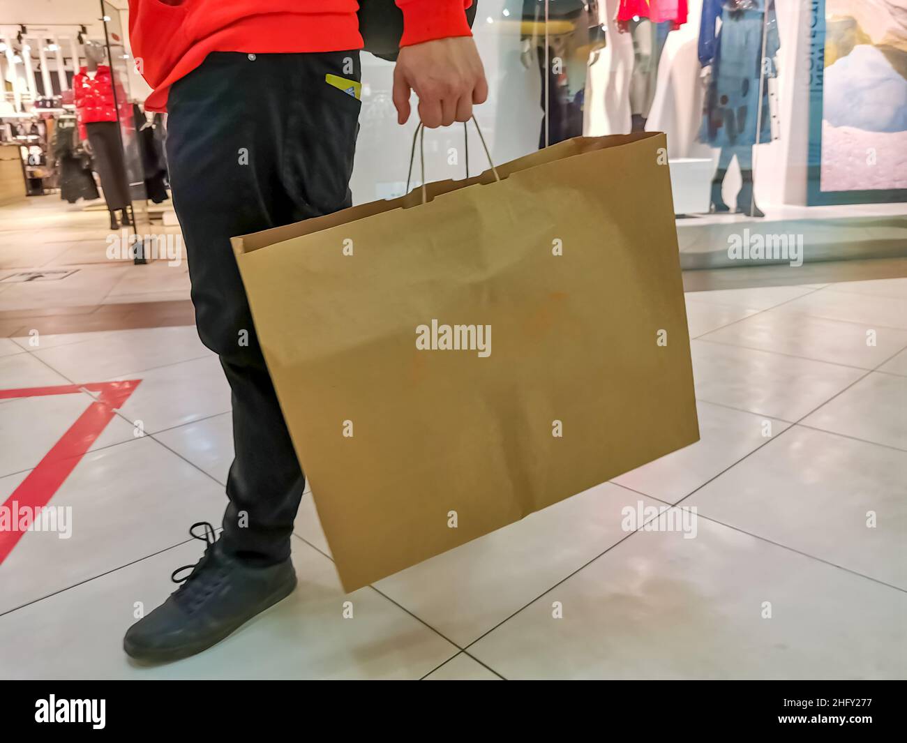 Gesichtsloser Mann, der mit einer Basteltasche im Einkaufszentrum läuft. Black friday Konzept Stockfoto