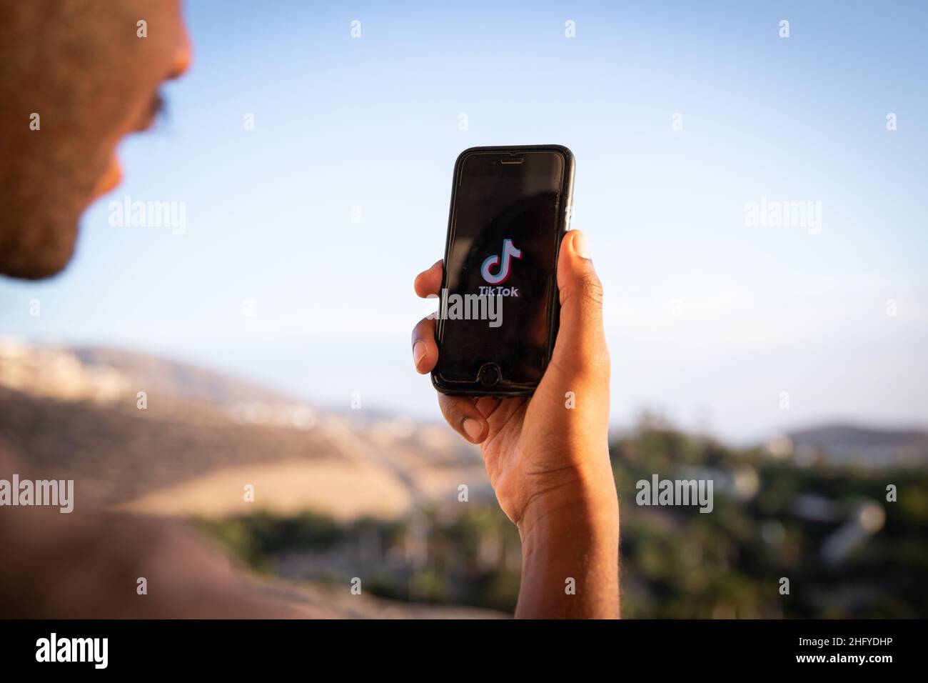 Ein Junge hält ein Smartphone mit dem TikTok-Logo, es ist eine sehr beliebte App und ein Video-fokussierter Social-Networking-Service Stockfoto