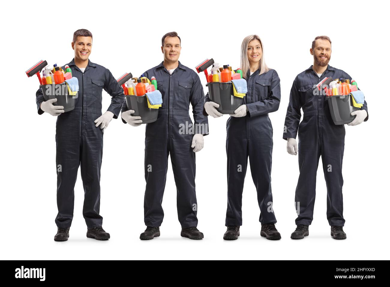 Gruppe von jungen professionellen Reinigungskräften in Uniformen, die Eimer mit Reinigungsmitteln auf weißem Hintergrund isoliert halten Stockfoto