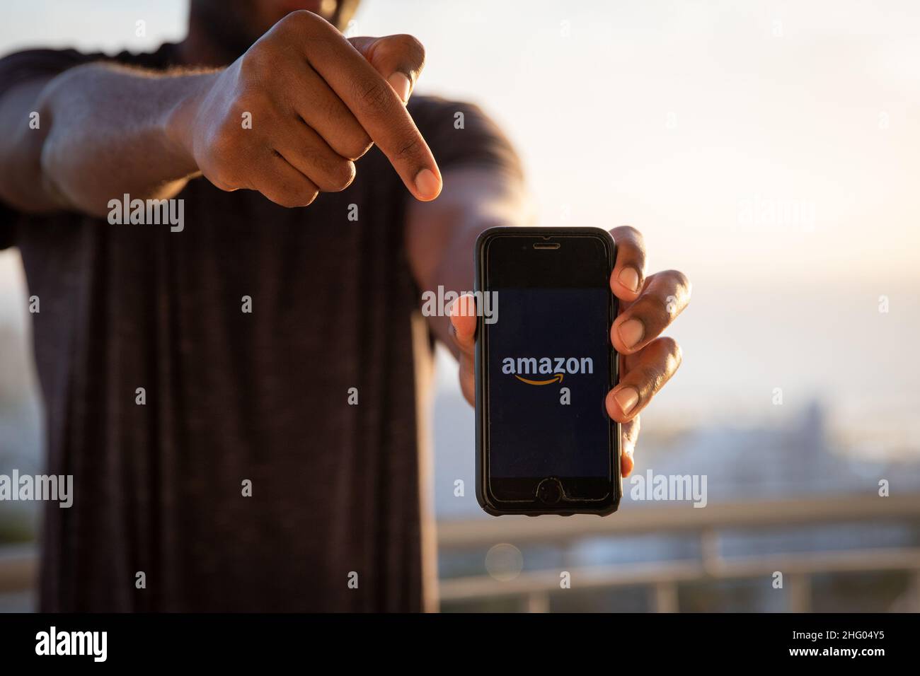 Ein Mann hält ein Smartphone mit dem Amazon-Logo. Ist ein US-amerikanisches multinationales Technologieunternehmen, das sich auf E-Commerce, Cloud-Computing und digitale e konzentriert Stockfoto