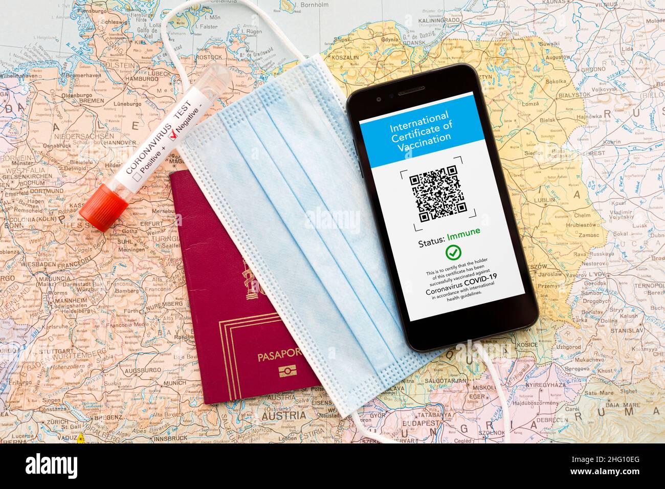 Draufsicht eines Mobiltelefons mit dem digitalen Impfzertifikat, medizinischer Maske, Pass und negativem Coronavirus-Test auf einer Karte. Covid-Pass Stockfoto