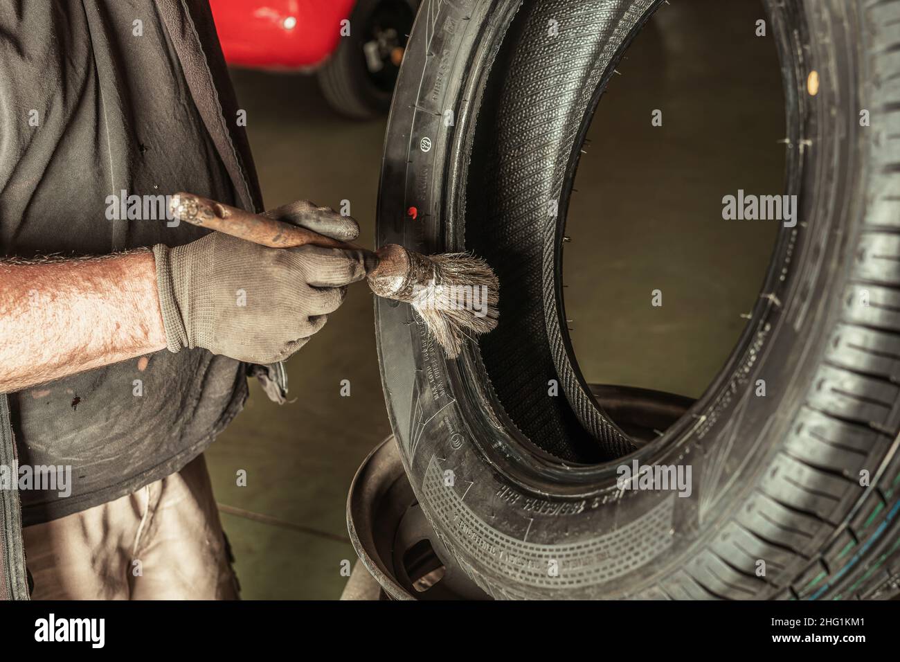Mann, der in der Werkstatt eines Mechanikers Schmiermittel auf ein Rad applyte. Stockfoto