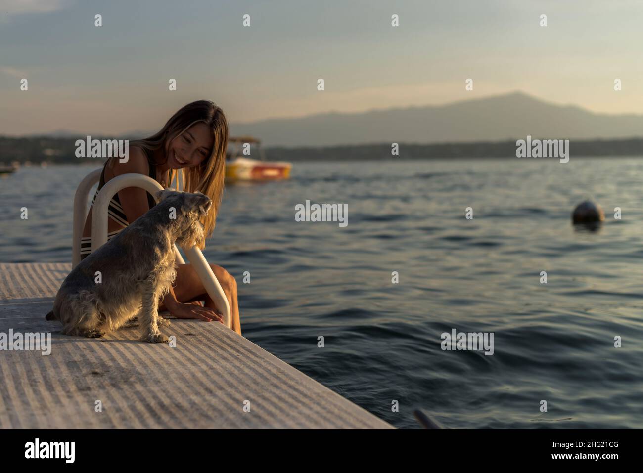 Ein süffeliges latinerin mit ihrem Hund Schnauzer am See an einem Nachmittag Stockfoto