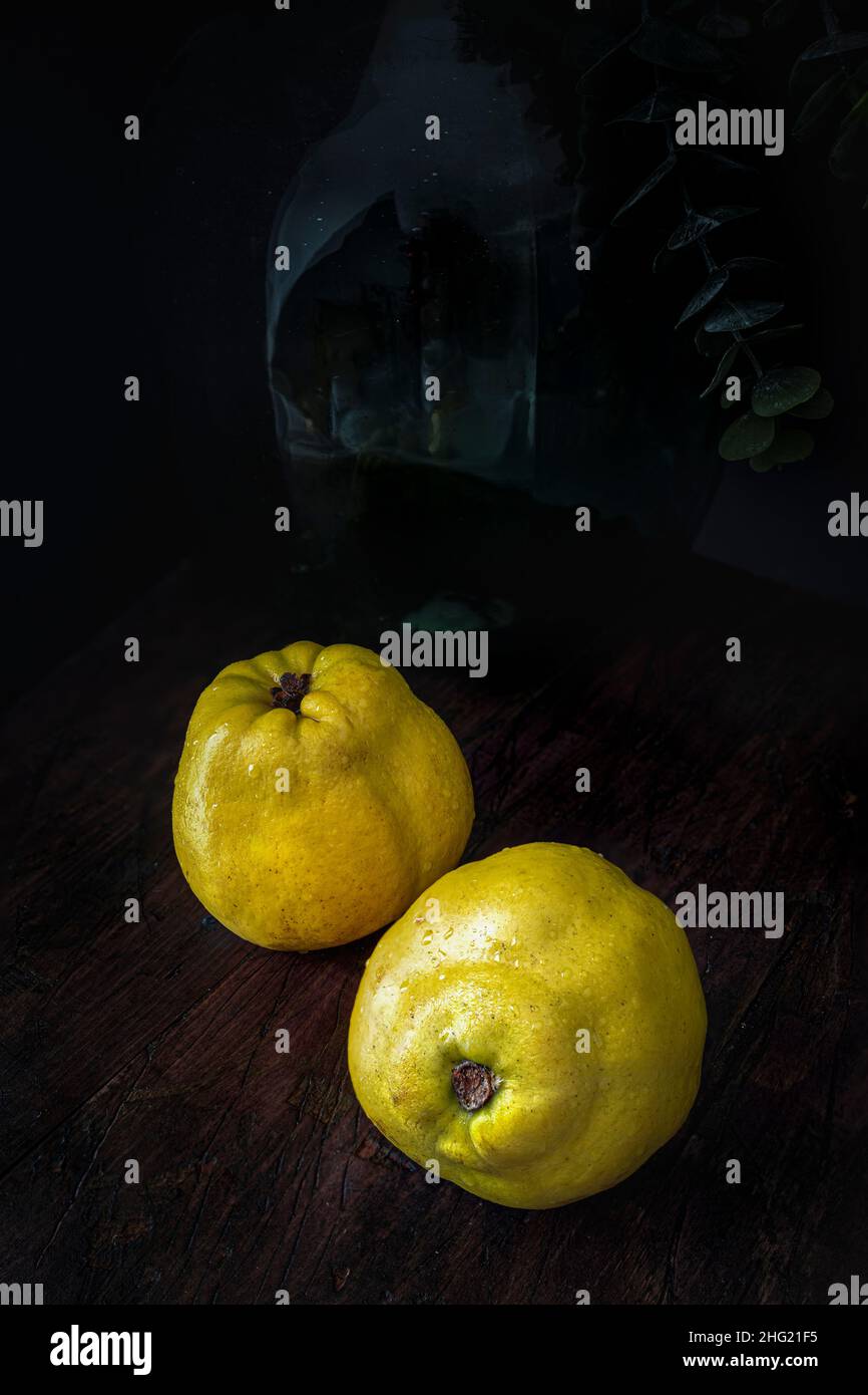 Reife Quitten auf einem hölzernen Küchentisch. Food-Fotografie mit dunkler Stimmung Stockfoto