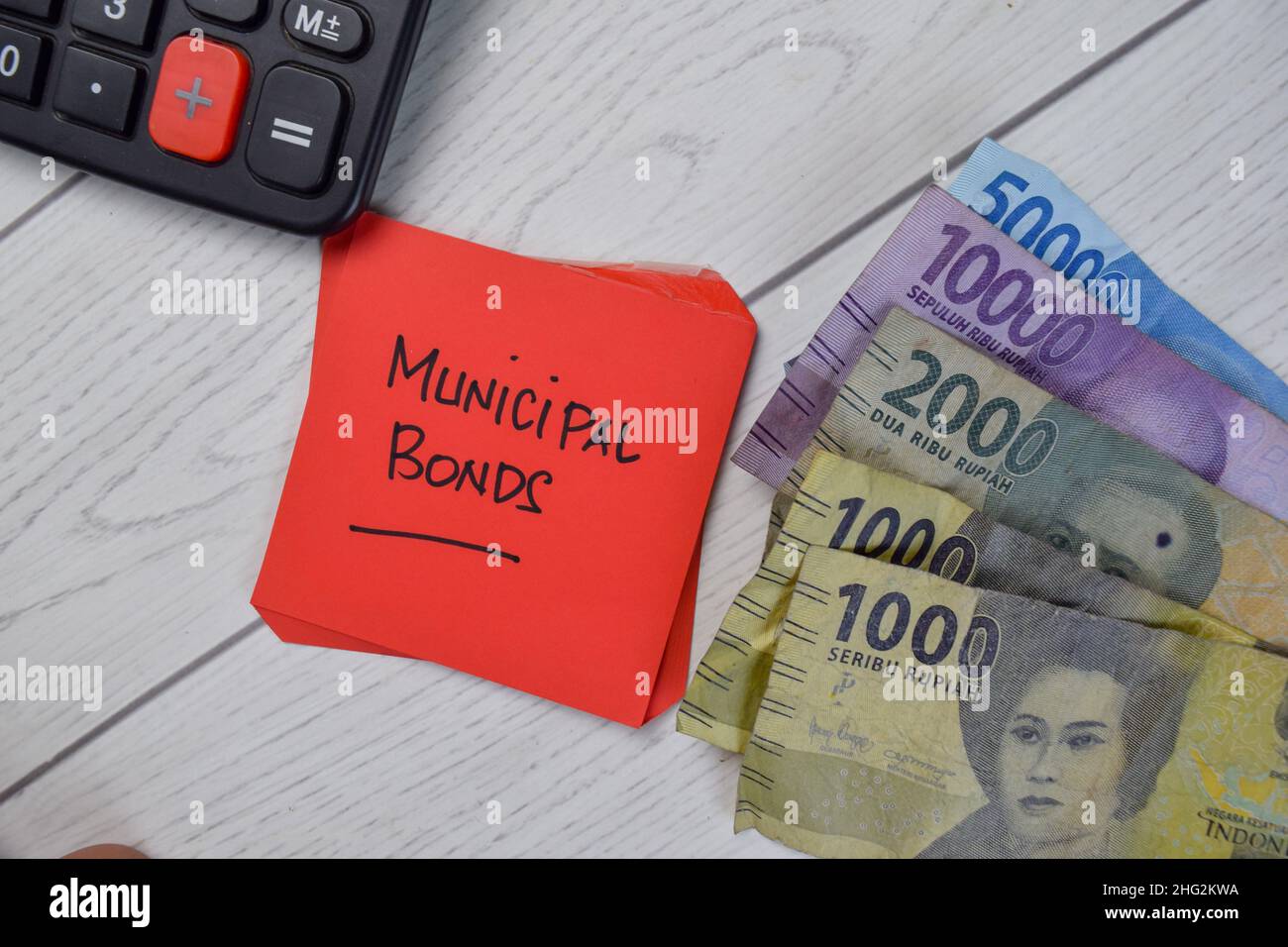 Kommunale Anleihen und indonesische Währung schreiben auf Haftnotizen isoliert auf Holztisch. Stockfoto