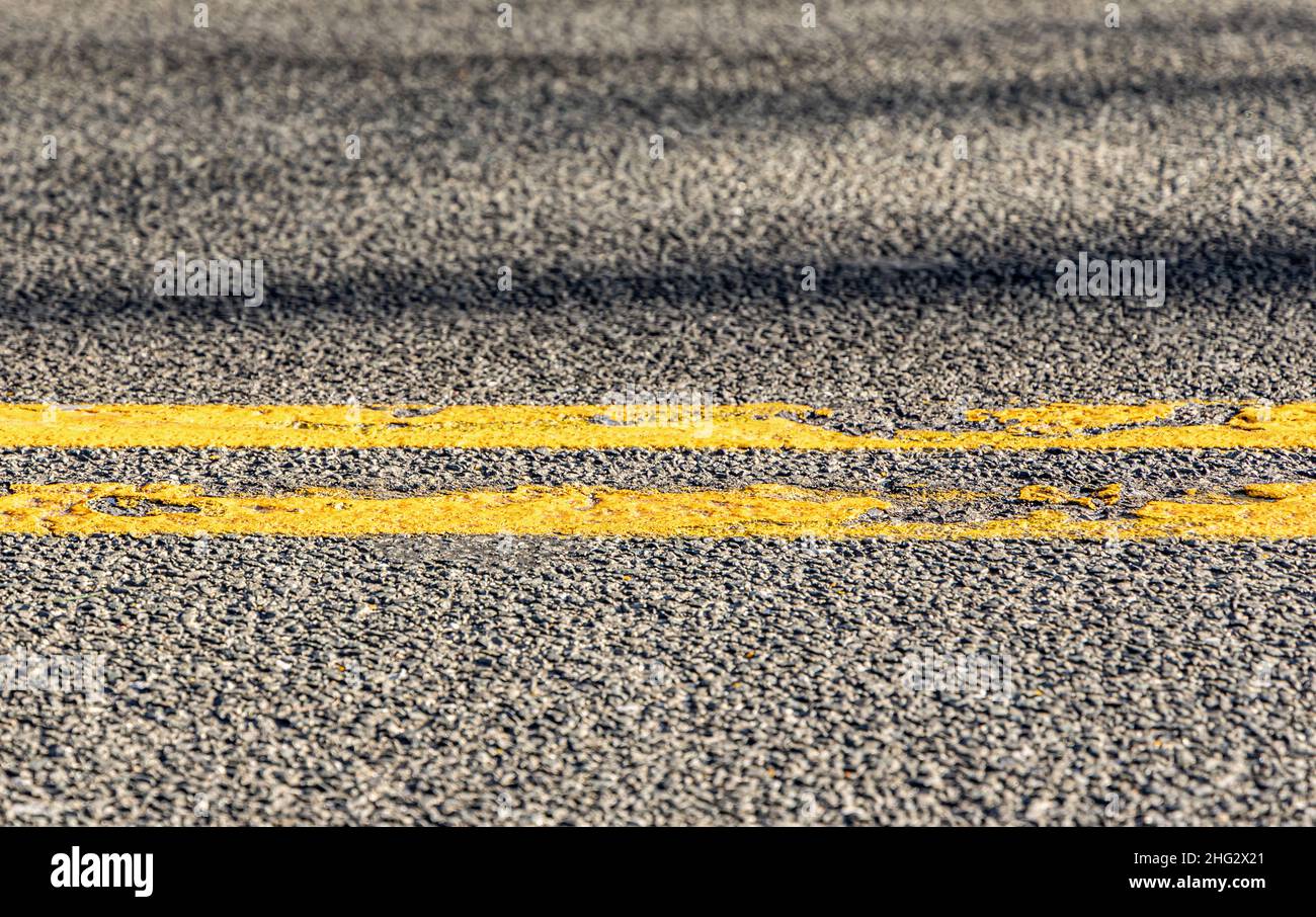 Detail einer zweifachen gelben Linie auf einer asphaltierten Straße Stockfoto