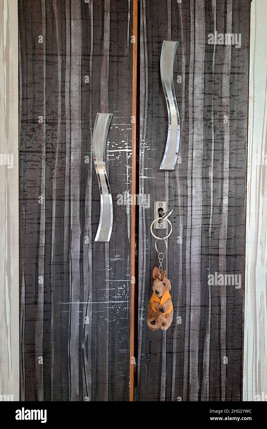 Nahansicht eines Teils der laminierten Schranktür mit Griffen, Schlüsselloch und Schlüsselbundchen Stockfoto