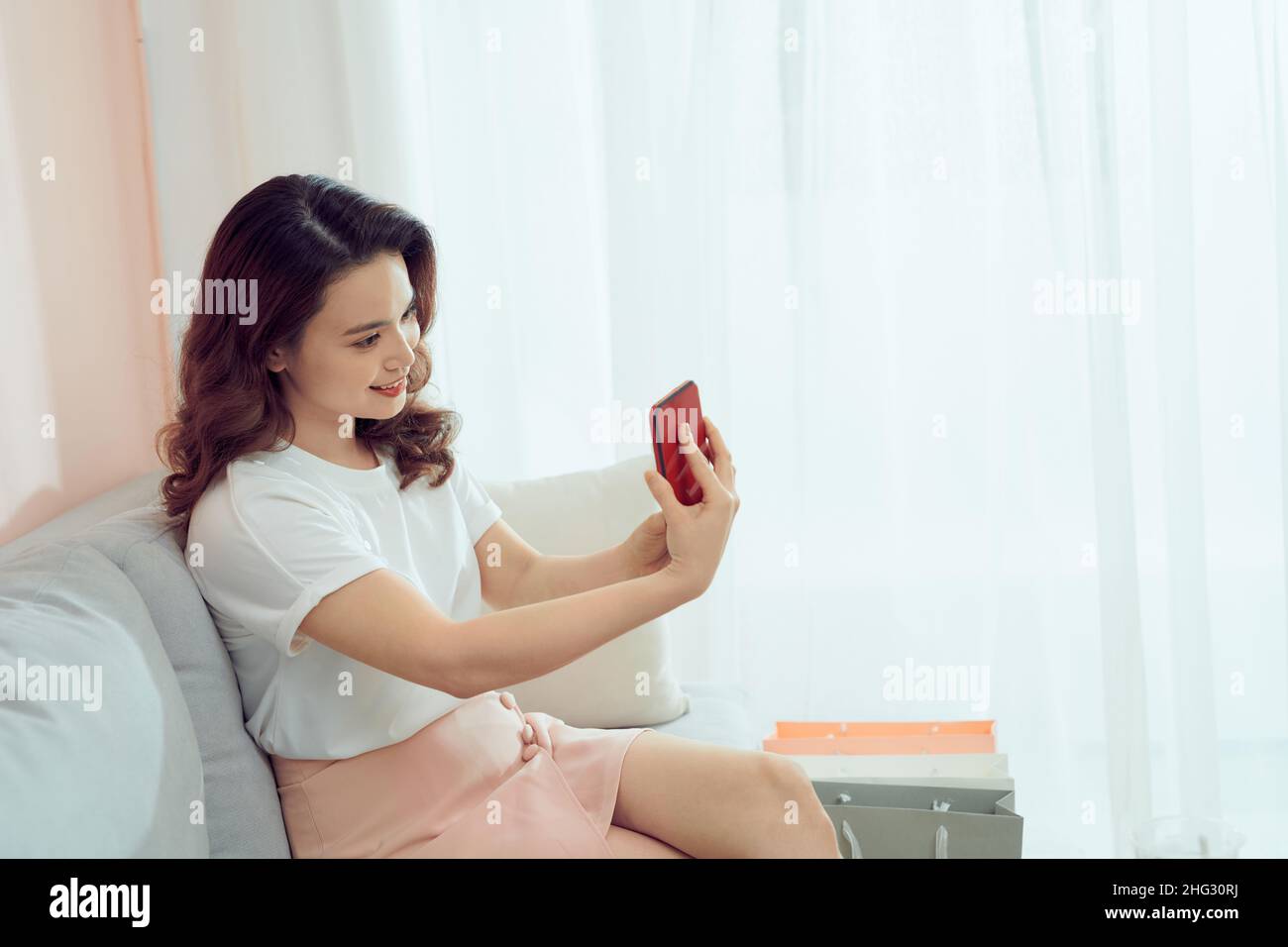 Lächelnde Geschäftsfrau, die im Heimbüro mit dem Handy fotografiert Stockfoto