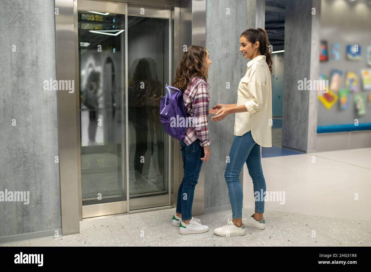 Frau und ein Mädchen reden vor den geschlossenen Aufzugstüren Stockfoto
