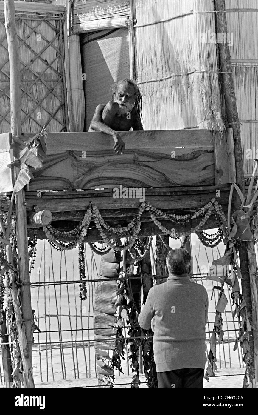Der Inder Siddha Yogi saint Devraha Baba sitzt auf seiner machan, einer hohen Holz- und Strohplattform, während er am Ufer des Yamuna-Flusses am 2. Februar 1989 in der Nähe von Vrindavan, Indien, eifrige Anhänger empfängt. Stockfoto