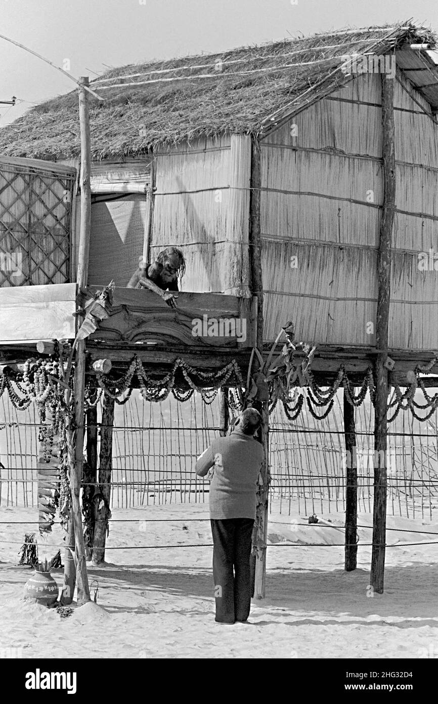 Der Inder Siddha Yogi saint Devraha Baba sitzt auf seiner machan, einer hohen Holz- und Strohplattform, während er am Ufer des Yamuna-Flusses am 2. Februar 1989 in der Nähe von Vrindavan, Indien, eifrige Anhänger empfängt. Stockfoto