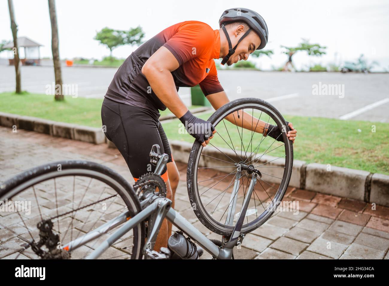 asiatischer Radler überprüft seinen Rennrad-Reifen Stockfoto