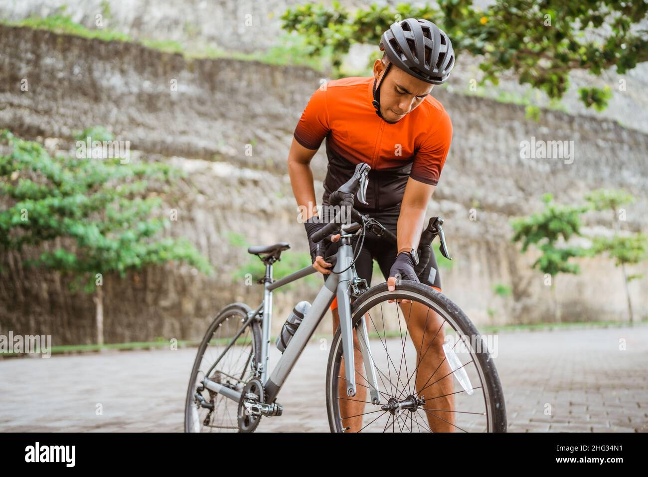 asiatischer Radler überprüft seinen Rennrad-Reifen Stockfoto