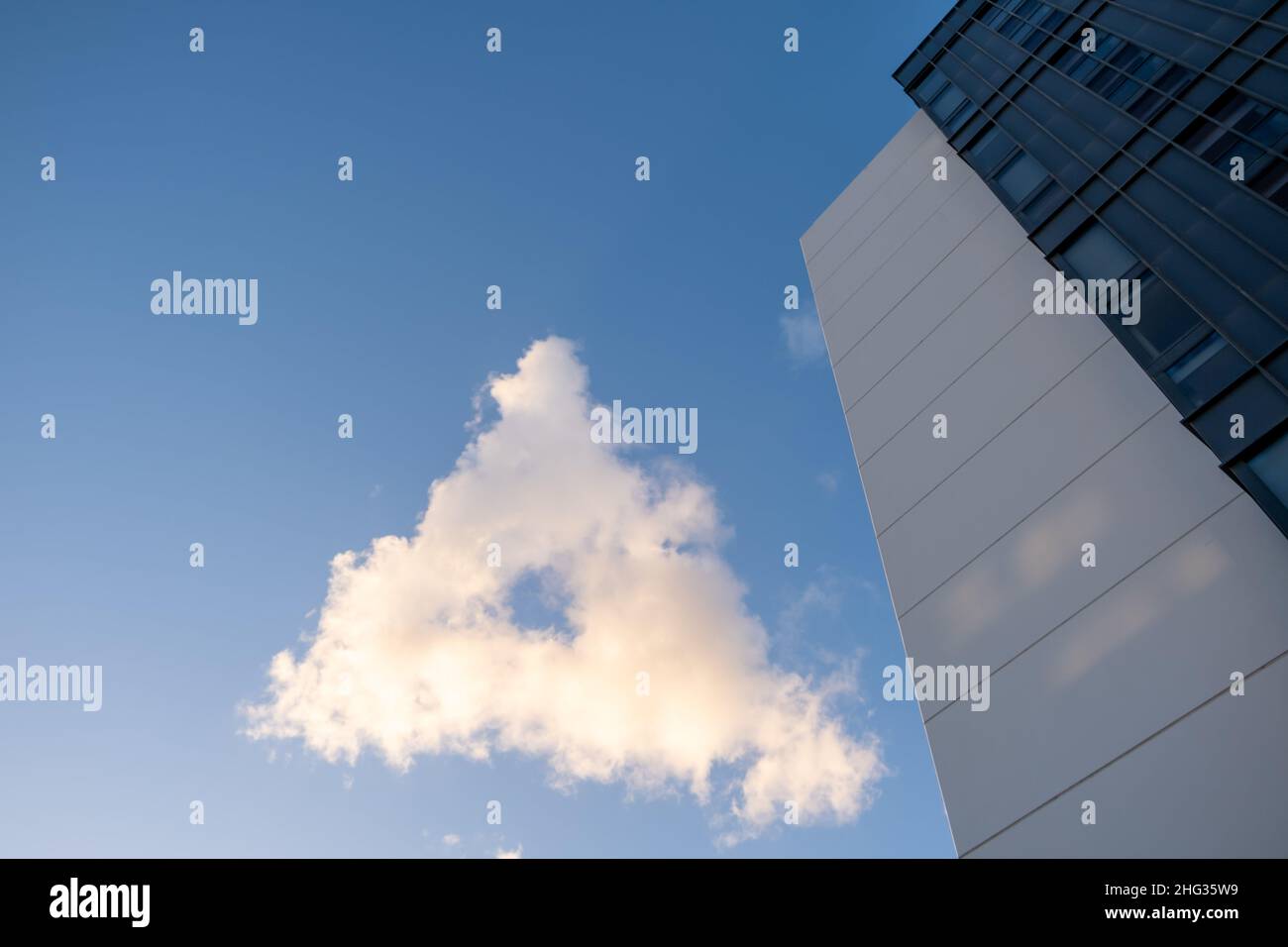 Dreieckige Wolke am blauen Himmel bei Sonnenuntergang mit modernem Wohnhaus - Blick nach oben Stockfoto