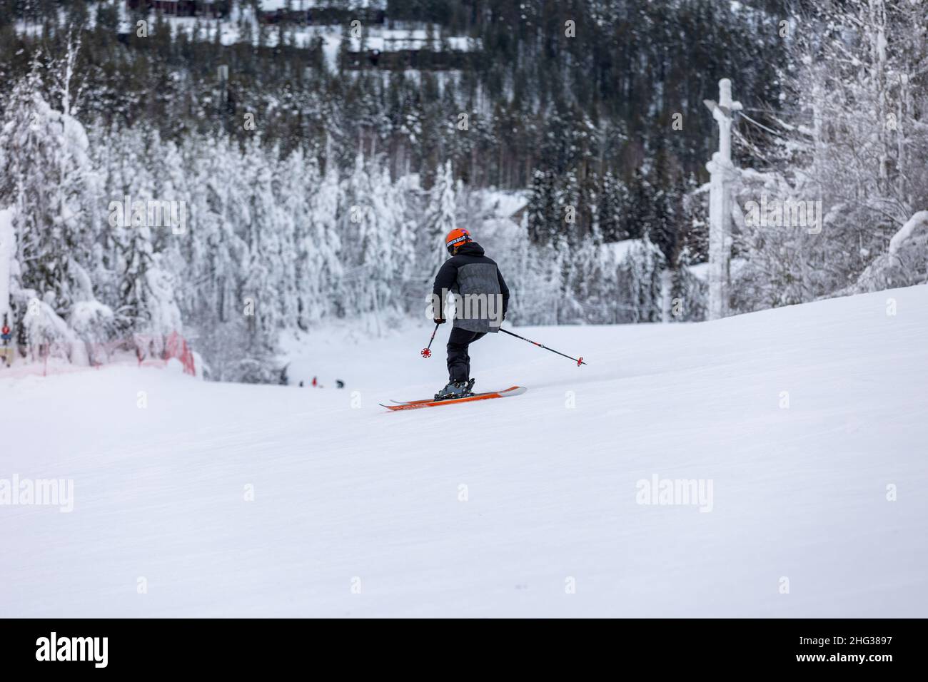 Vuokatti, Finnland - January2022: Kleiner Junge, der mit hoher Geschwindigkeit die Piste hinunter fährt. Skifahrer, die sehr schnell die Schanze hinunter fahren. Stockfoto