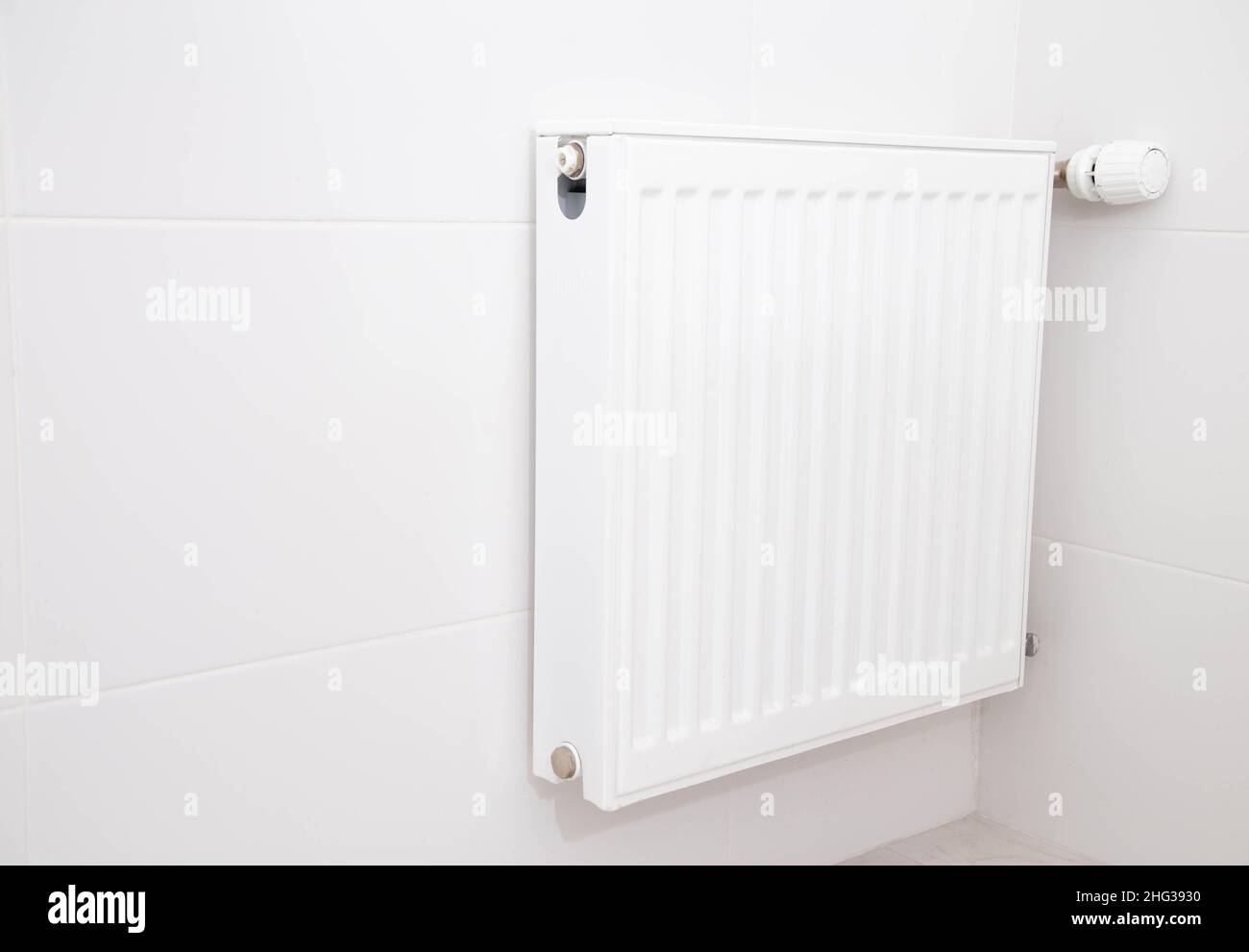 Moderner wandmontierter Heizkörper mit Thermostat an der weißen Wand im Badezimmer. Die Temperatur im Bad war komfortabel Stockfoto