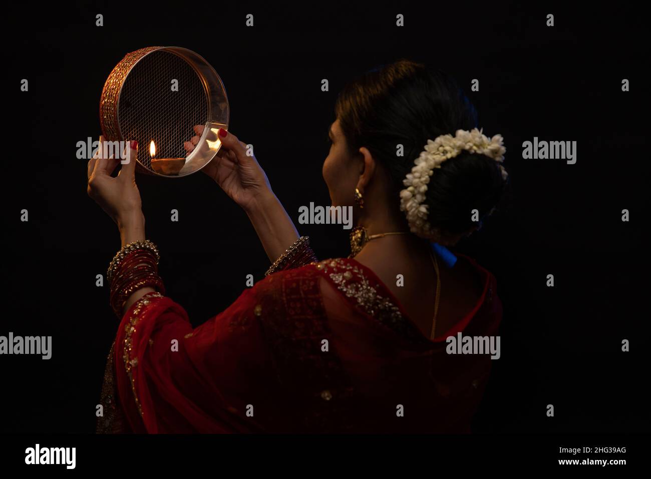 Frau, die während Karva Chauth durch ein Sieb den Mond ansah Stockfoto